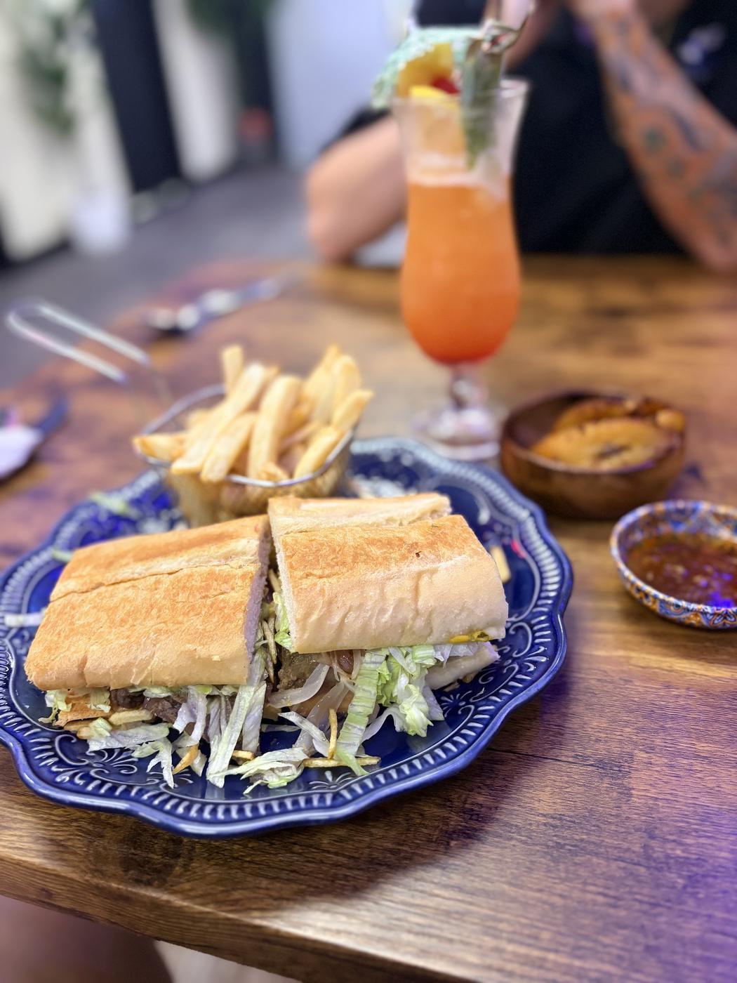 Pan con Bistec on a blue plate with fries